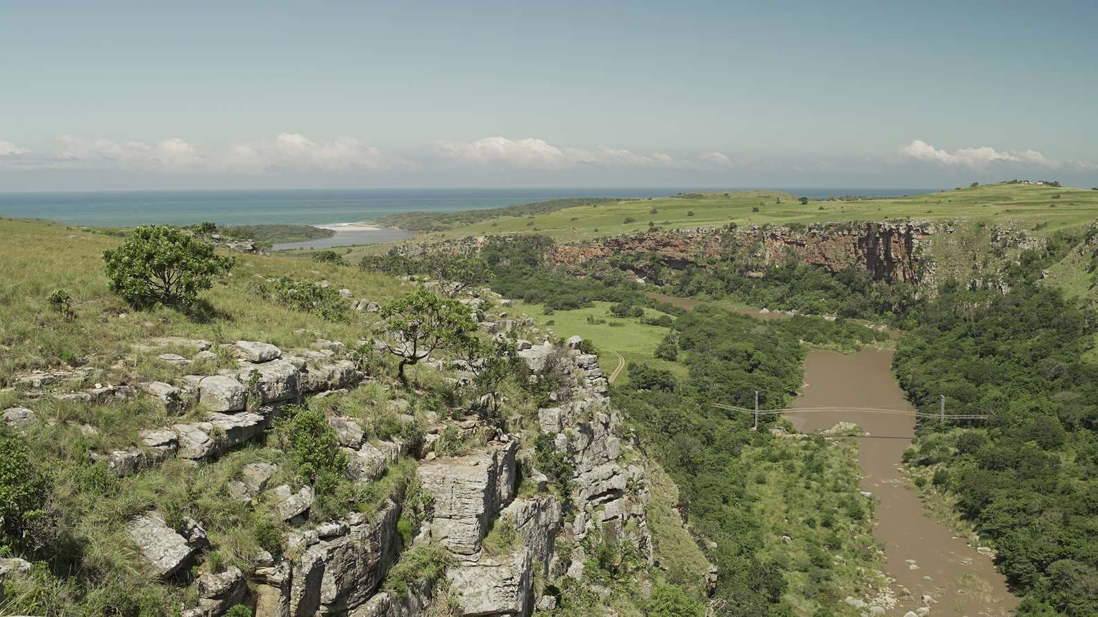 Aerial view of rocky gorge and green coastal scrubland above the Mzamba River mouth, Wild Coast South Africa