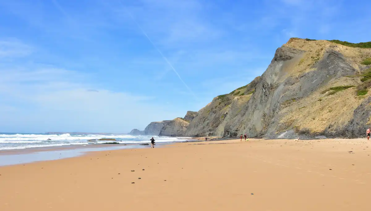 Lone hiker on a vast empty sandy beach beneath towering cliffs on the Wild Coast, Eastern Cape, South Africa