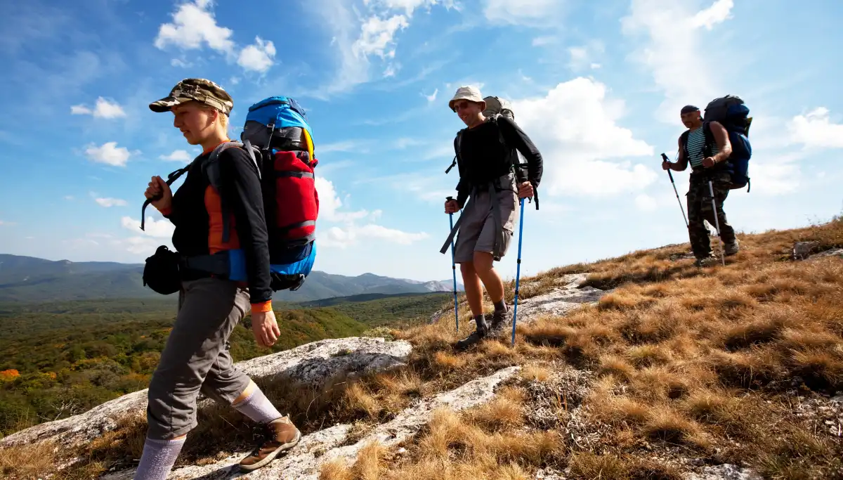 Group of three hikers with full backpacks ascending a rocky ridge on a guided Wild Coast hiking trail, South Africa