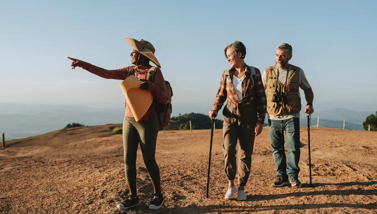 Guide pointing toward the ocean while leading two hikers on a hilltop during a guided Wild Coast hiking tour, South Africa
