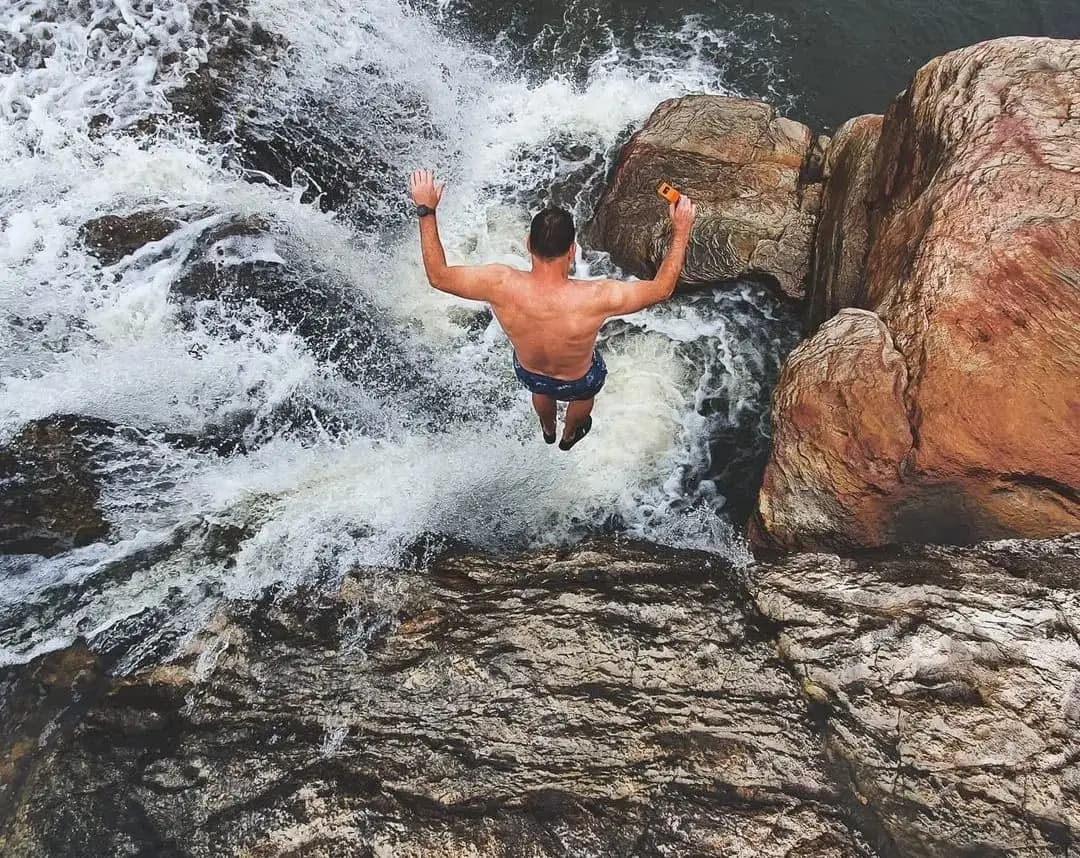 Hiker jumping off rocks into the Jacuzzi Hole natural pool at Mkambathi Falls Wild Coast