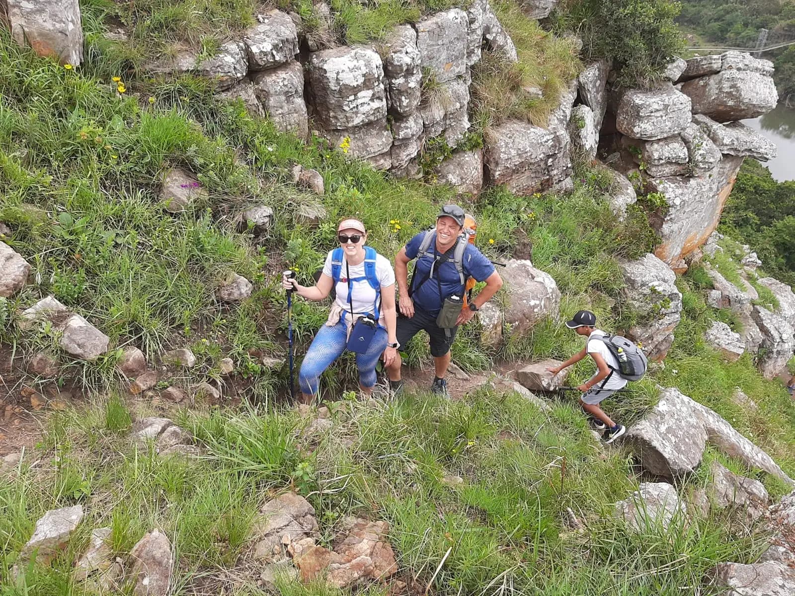 Three hikers scrambling up the steep rocky walls of the Mzamba gorge on the Mtentu Ramble, Eastern Cape