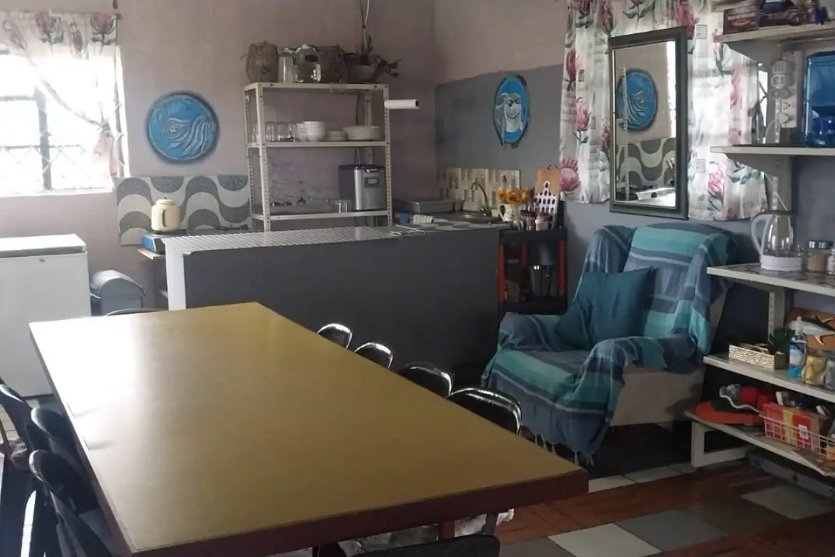 Simple homely dining room inside the Hiking Shack Wild Coast stopover with yellow table and green armchair