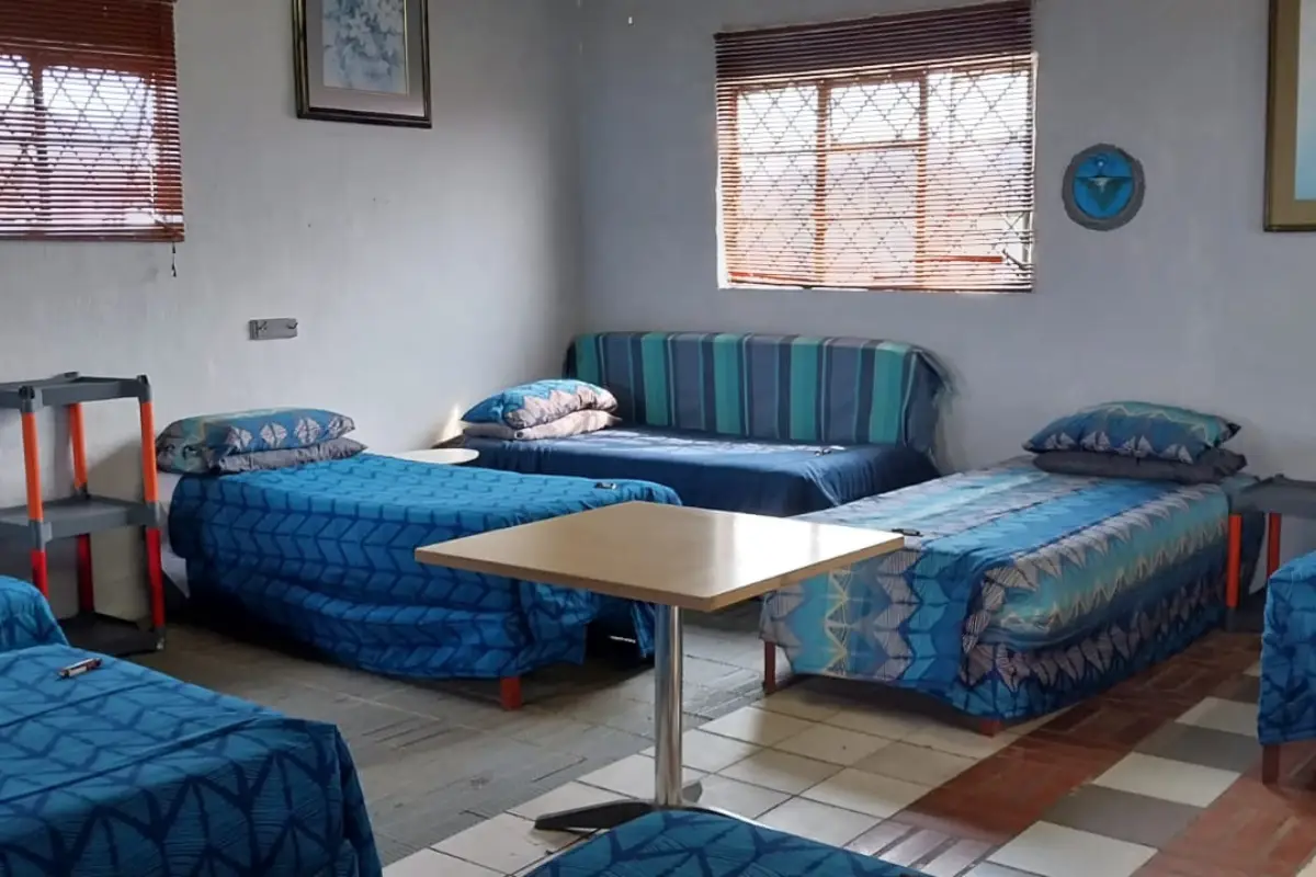 Clean dormitory room at the Hiking Shack Wild Coast with multiple single beds and blue linen