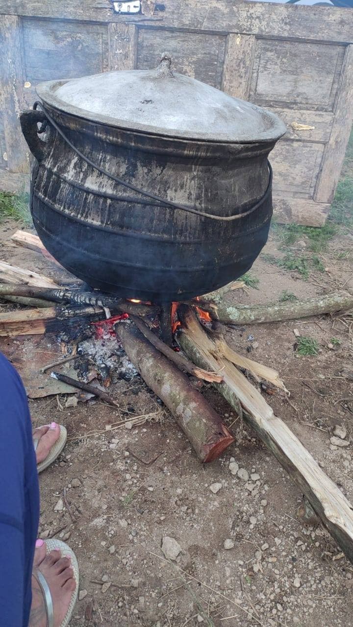 Black cast-iron potjie pot heating water over open wood fire at Mnyameni Pondoland homestead