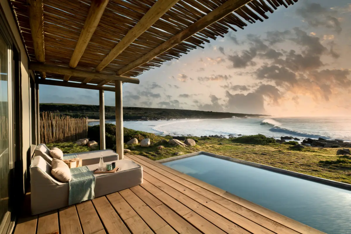 Infinity plunge pool and lounge chairs on a wooden deck at GweGwe Beach Lodge overlooking the Wild Coast at dusk