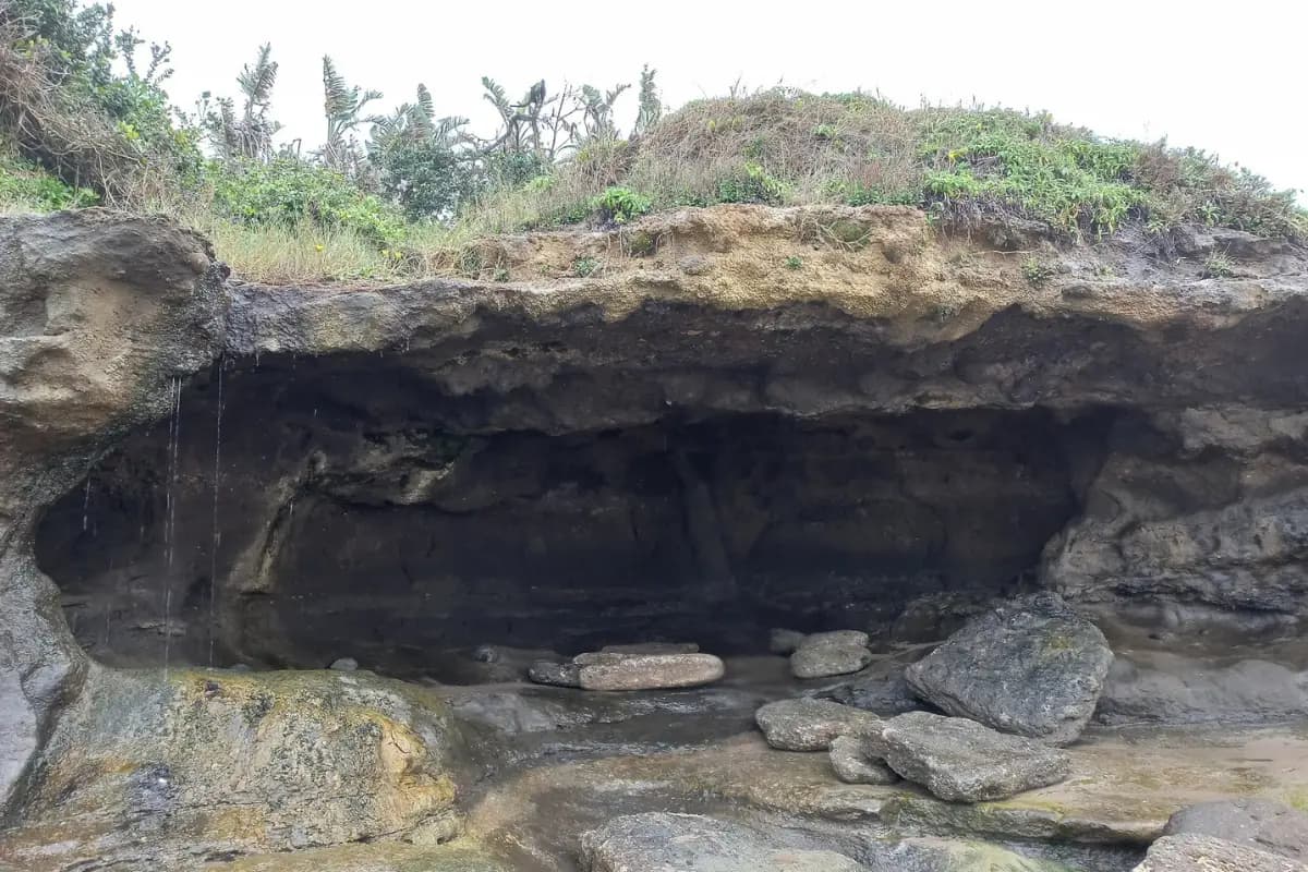 Large rock overhang forming a cave with boulders on the floor at Mzamba coastline, Wild Coast Eastern Cape