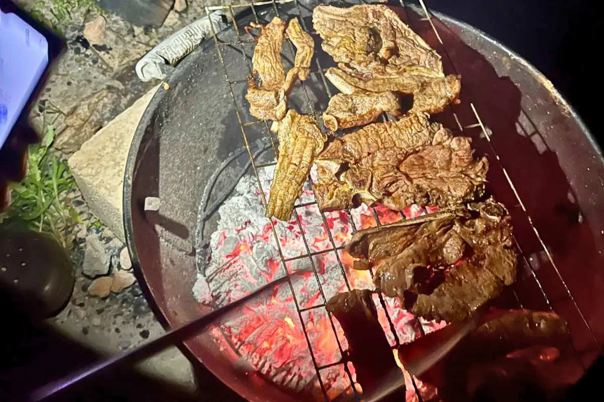 Chicken and steak grilling over glowing red coals on a traditional South African braai in Pondoland