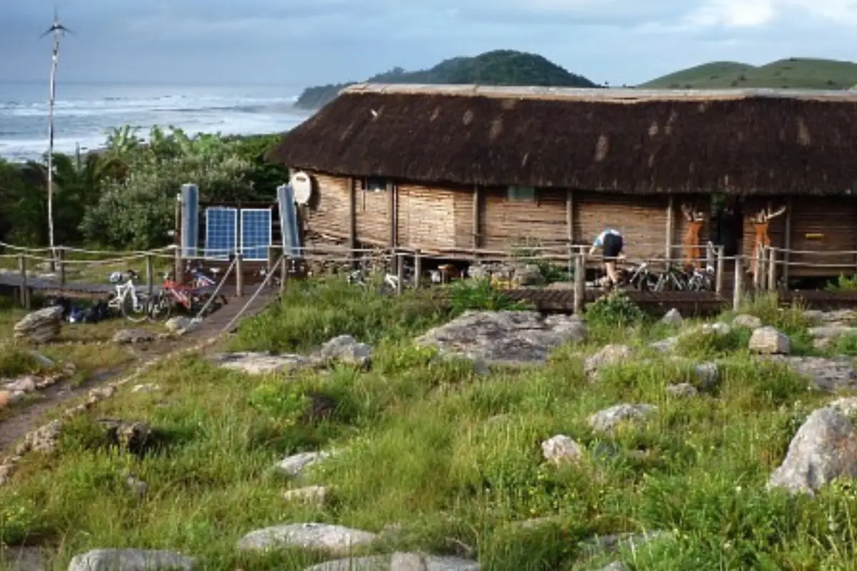 Mtentu Lodge thatched main building on rocky Wild Coast hillside with ocean and headland behind