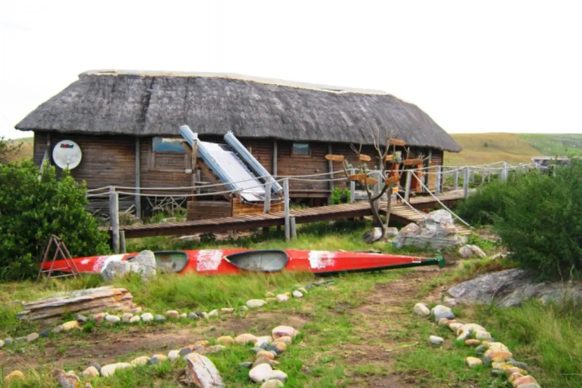 Mtentu Lodge Wild Coast with red kayaks stored outside the thatched building beside the rocky shoreline