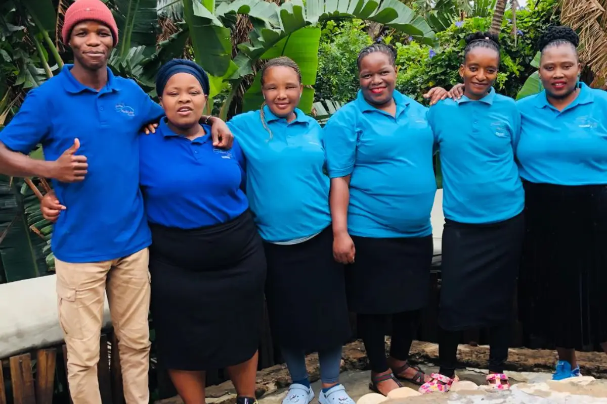 Six Mtentu Lodge staff members in blue polo shirts posing together outdoors, Wild Coast South Africa