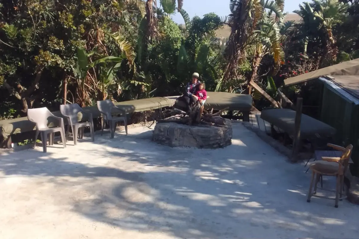 Hikers sitting around the new outdoor fire pit at Mtentu Lodge surrounded by tropical coastal vegetation