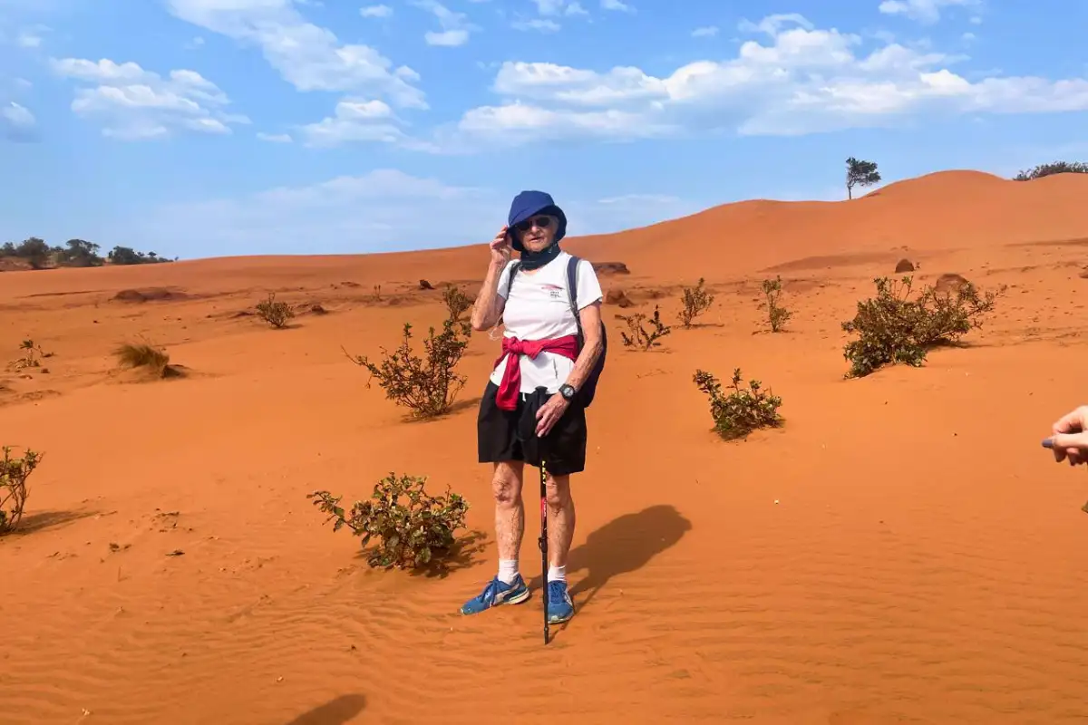 Hiker standing alone among vast red sand dunes in Pondoland Eastern Cape, South Africa under a wide blue sky