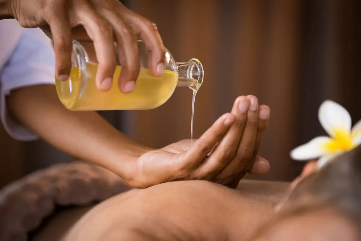 Therapist pouring golden massage oil onto hand during a treatment at Pamper Shack near Mtentu River, Wild Coast