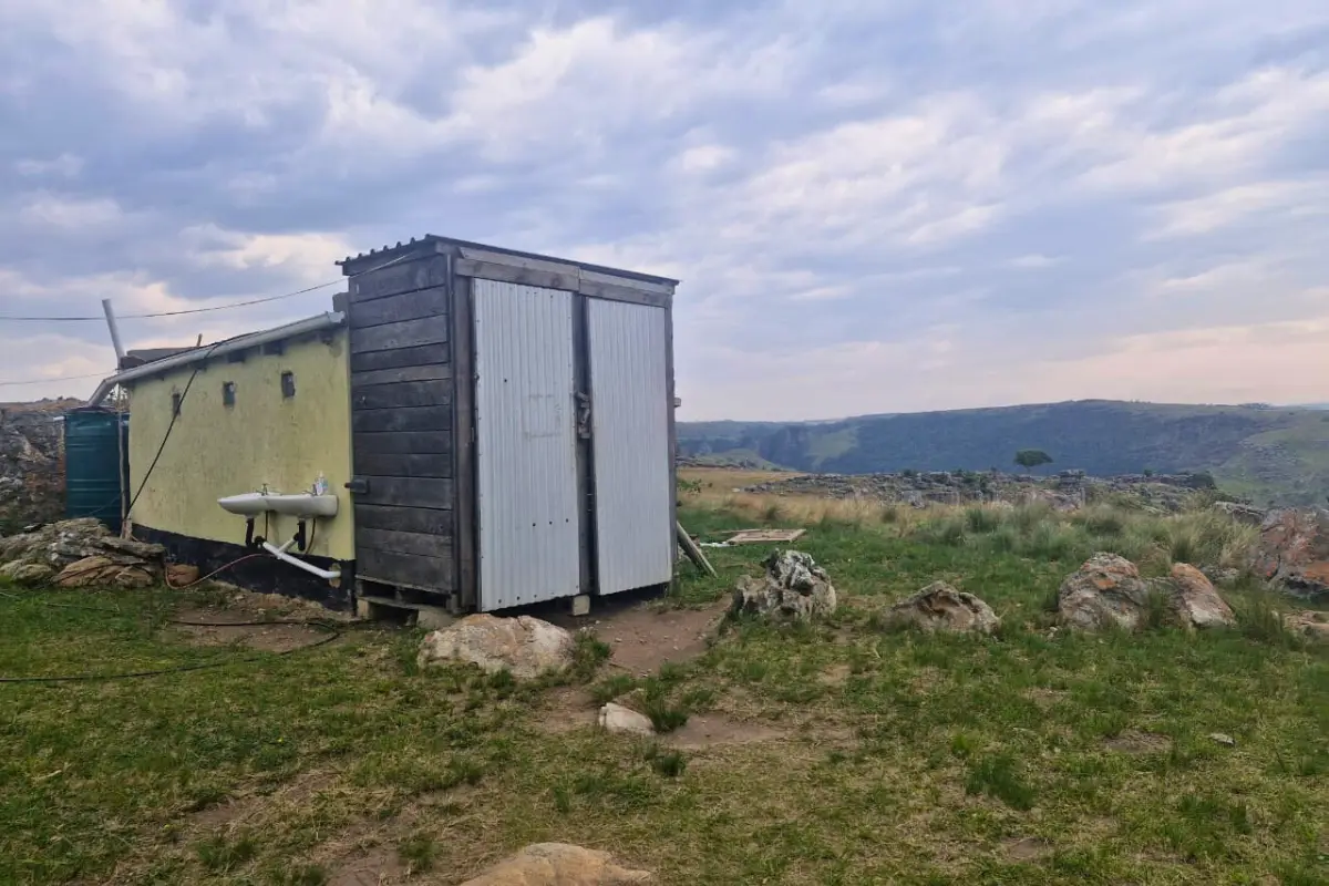 Rustic outdoor toilet and bucket shower cubicle on a hilltop at a Wild Coast hiking homestay, Eastern Cape