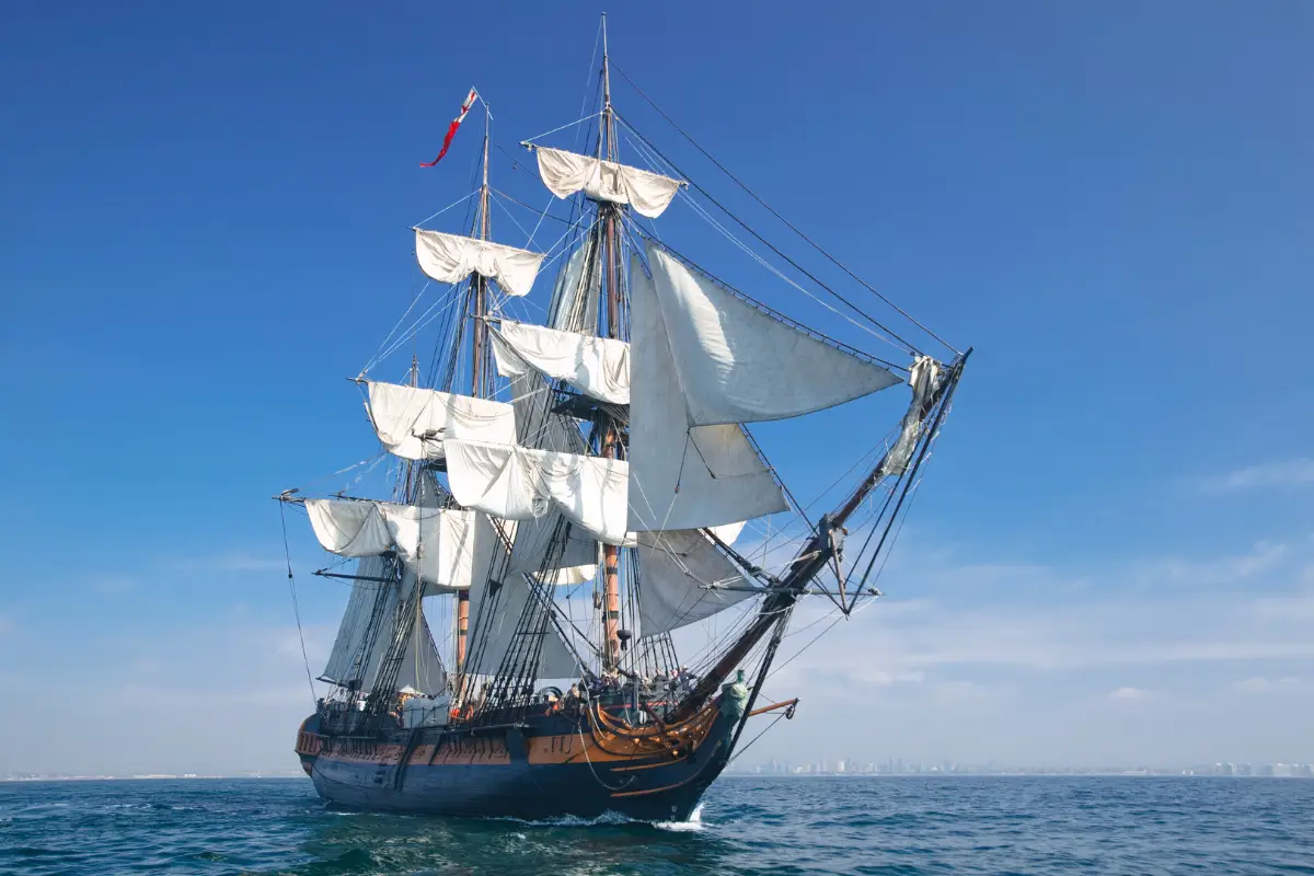 Classic tall ship under full sail on open blue ocean, representing British vessels that sailed treacherous Wild Coast waters for centuries