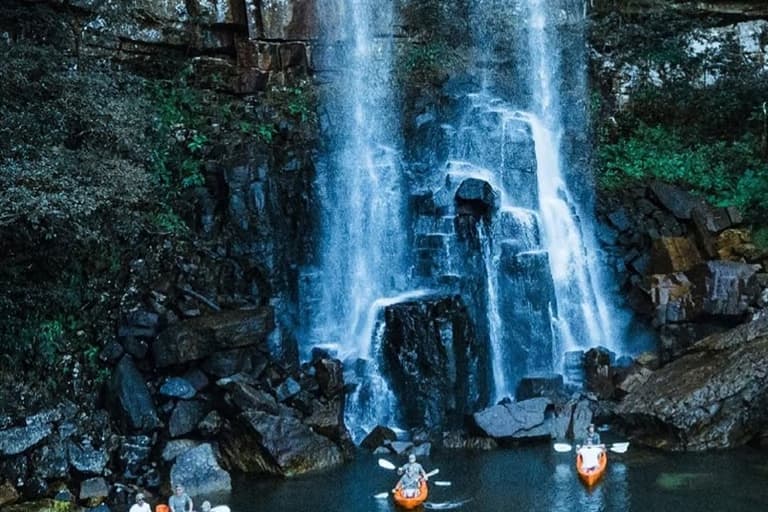 Two swimmers floating in the plunge pool beneath Leopard Rock Falls on the Mtentu River, Pondoland