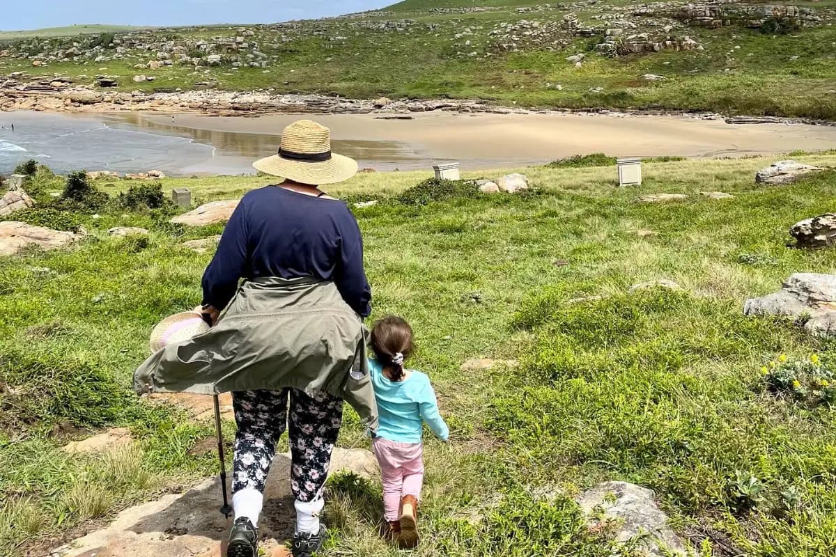 Woman and young child walking toward sandy river mouth beach at Mtentu on the Wild Coast